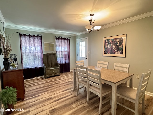 dining area with crown molding, light wood-type flooring, and an inviting chandelier