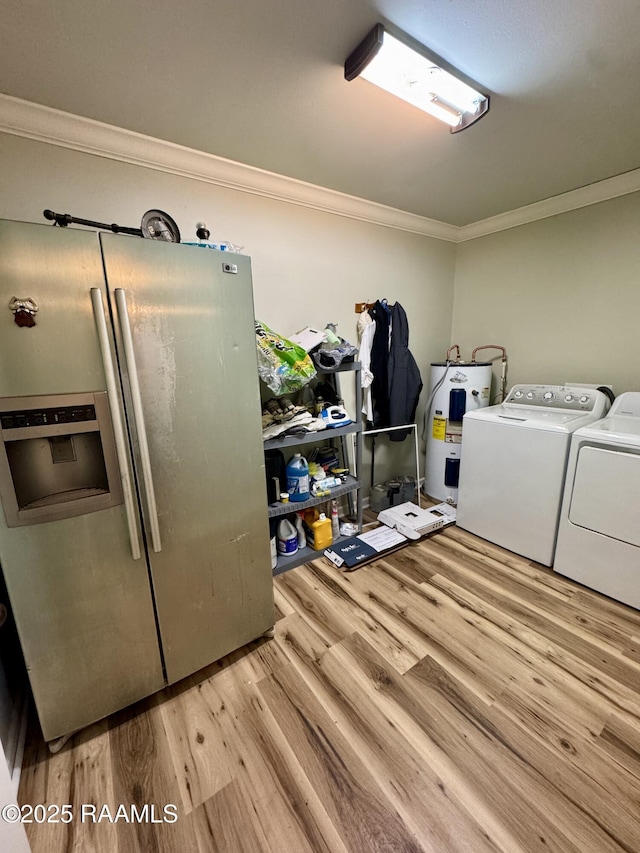 clothes washing area featuring crown molding, water heater, laundry area, wood finished floors, and washer and dryer