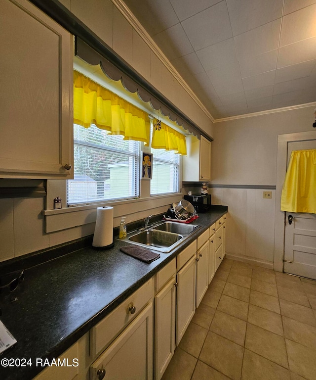 kitchen with light tile patterned floors, ornamental molding, and sink