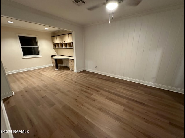 unfurnished living room with built in desk, ceiling fan, ornamental molding, and dark hardwood / wood-style flooring