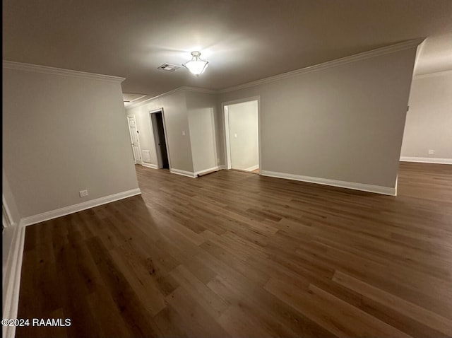 spare room with ornamental molding and dark wood-type flooring