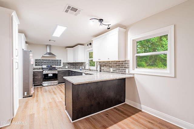 2862 S Union St, Opelousas, LA 70570 - kitchen with stainless steel appliances, wall chimney exhaust hood, a peninsula, tasteful backsplash, and white cabinets