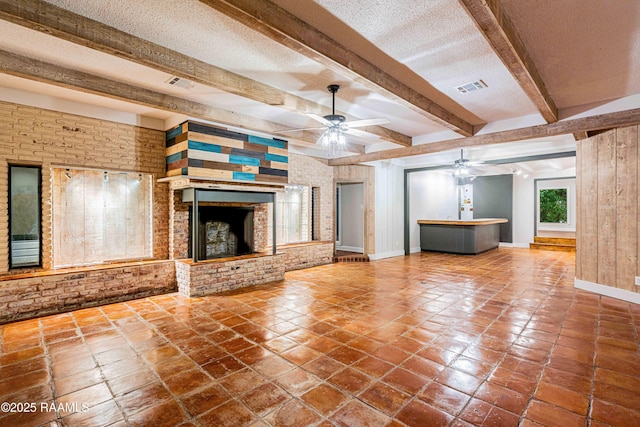 2862 S Union St, Opelousas, LA 70570 - unfurnished living room with a ceiling fan, baseboards, beamed ceiling, a textured ceiling, and brick wall