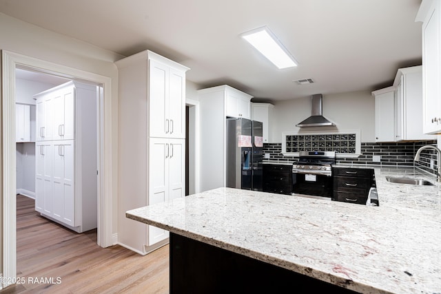 2862 S Union St, Opelousas, LA 70570 - kitchen featuring stainless steel range with gas cooktop, wall chimney exhaust hood, a sink, refrigerator with ice dispenser, and light wood-type flooring