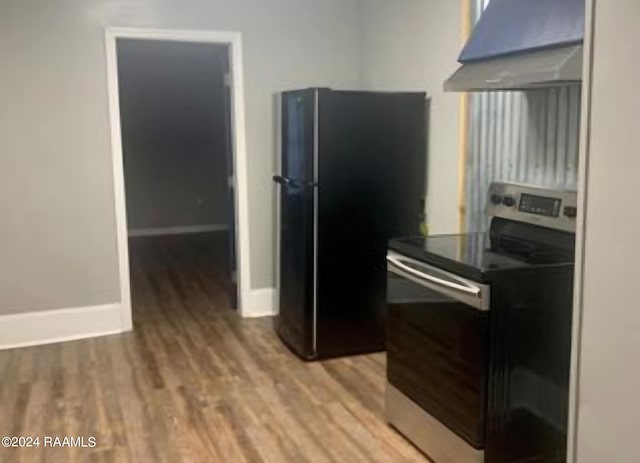 kitchen with wood-type flooring, wall chimney exhaust hood, electric stove, and black fridge