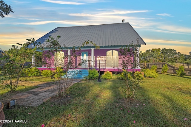 back house at dusk featuring a yard