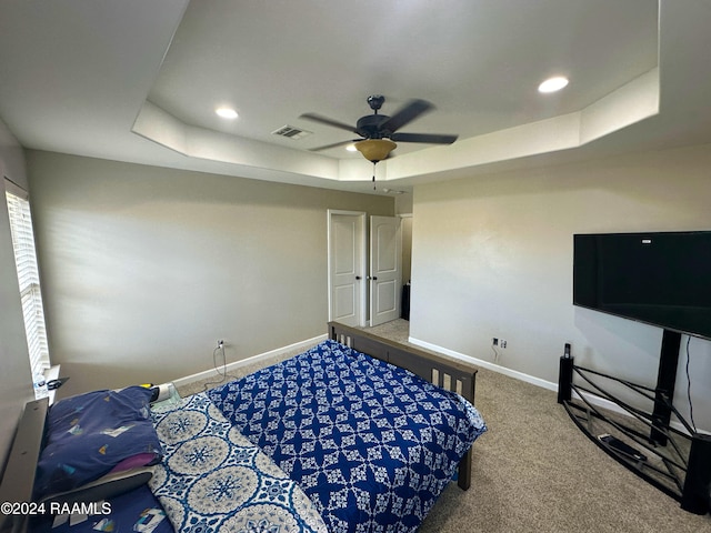 bedroom featuring carpet, ceiling fan, and a tray ceiling