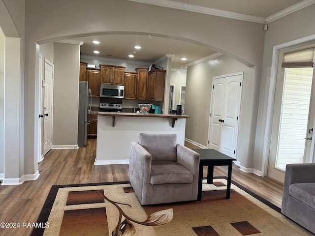 living room with light hardwood / wood-style flooring, crown molding, and a healthy amount of sunlight