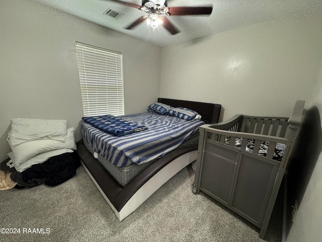 carpeted bedroom featuring ceiling fan and a textured ceiling