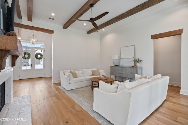 living room with light wood-type flooring, ceiling fan with notable chandelier, beam ceiling, and a brick fireplace