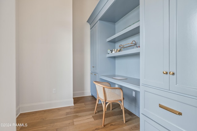 office with light hardwood / wood-style flooring and built in desk