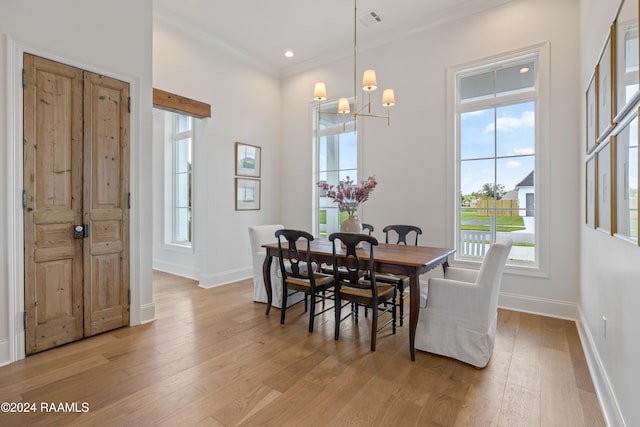 dining area featuring light hardwood / wood-style floors, ornamental molding, and an inviting chandelier