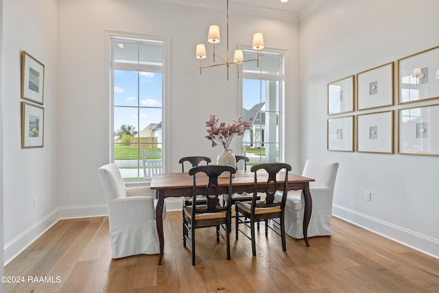 dining room with light wood-type flooring, ornamental molding, and a notable chandelier