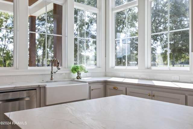 kitchen with white cabinets, dishwasher, light stone counters, and sink