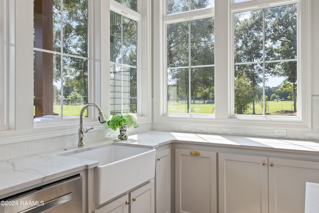 kitchen featuring light stone counters, white cabinets, and a wealth of natural light