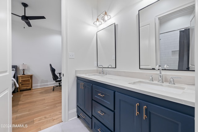 bathroom featuring wood-type flooring, a shower with shower curtain, ornamental molding, ceiling fan, and vanity