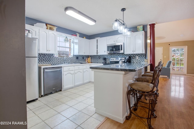 kitchen featuring white cabinets, a breakfast bar area, stainless steel appliances, and tasteful backsplash