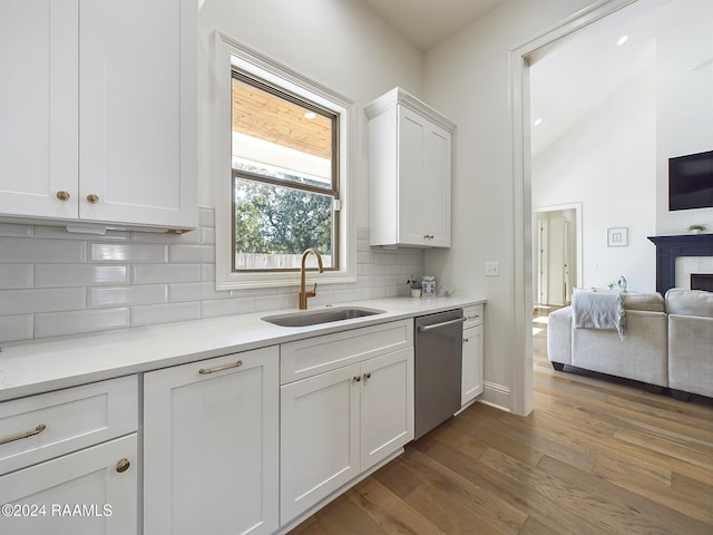 kitchen with decorative backsplash, white cabinets, dark hardwood / wood-style flooring, stainless steel dishwasher, and sink