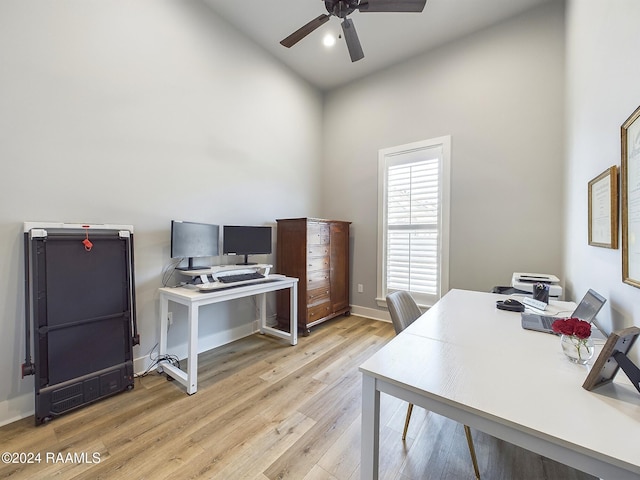 home office featuring ceiling fan, a towering ceiling, and light hardwood / wood-style flooring