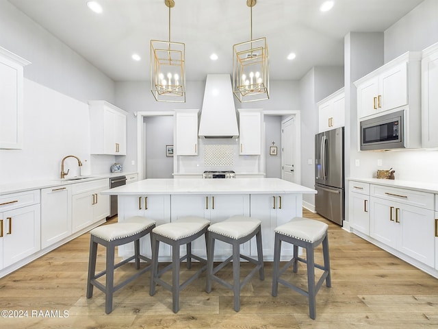 kitchen with a breakfast bar area, premium range hood, stainless steel appliances, and light wood-type flooring