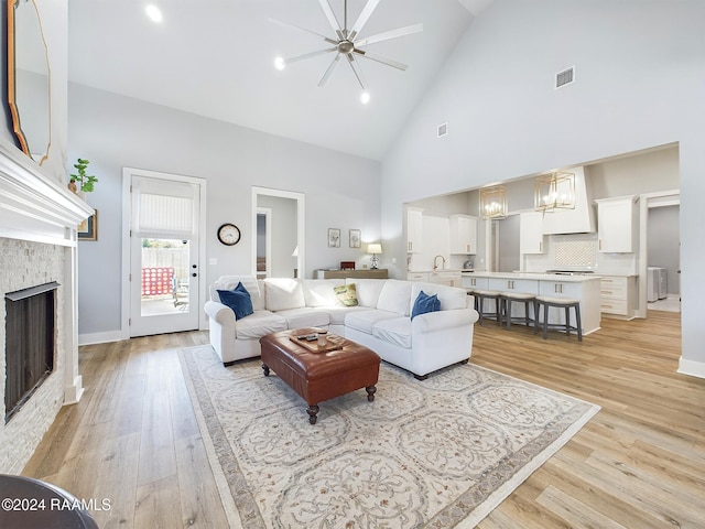 living room featuring light hardwood / wood-style floors, high vaulted ceiling, sink, and ceiling fan