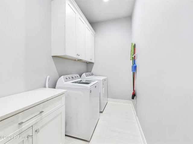 clothes washing area featuring cabinets and washing machine and clothes dryer