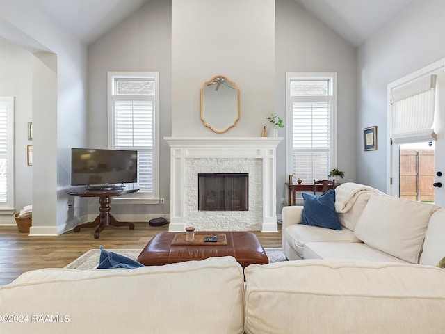 living room featuring high vaulted ceiling, a fireplace, and hardwood / wood-style floors