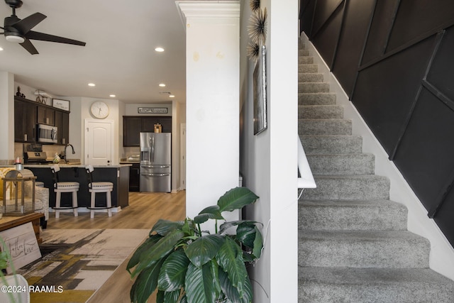 stairs with sink, ceiling fan, and hardwood / wood-style floors