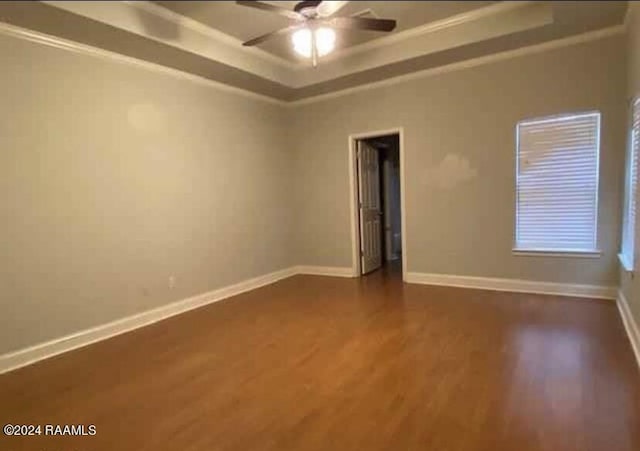 147 Oakbend Dr, Lafayette, LA 70506 - empty room with dark wood-style flooring, a ceiling fan, baseboards, a tray ceiling, and ornamental molding