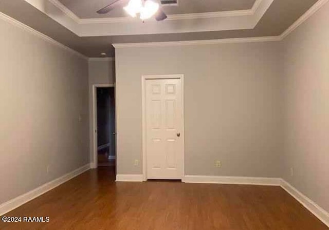 unfurnished bedroom featuring ceiling fan, a raised ceiling, dark wood-type flooring, and crown molding