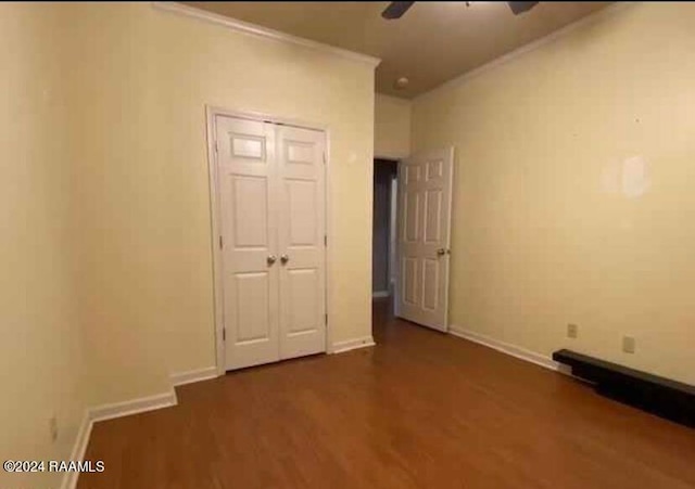 unfurnished bedroom featuring ceiling fan, a closet, dark wood-type flooring, and crown molding