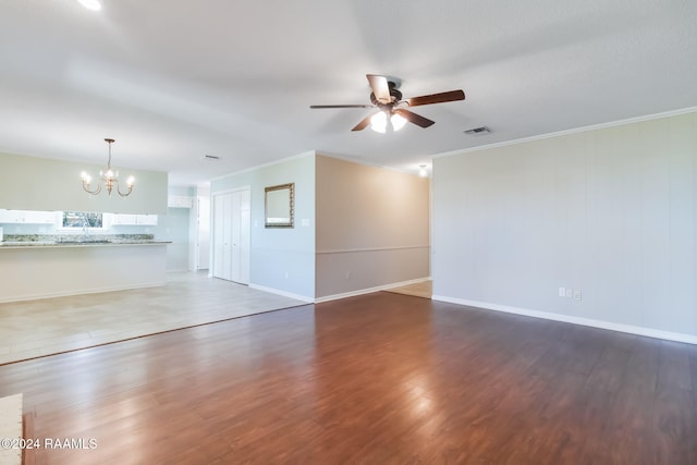 unfurnished living room with ceiling fan with notable chandelier, crown molding, and dark hardwood / wood-style flooring