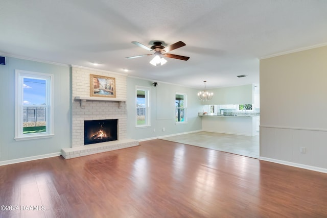 unfurnished living room featuring a brick fireplace, hardwood / wood-style flooring, plenty of natural light, and ornamental molding