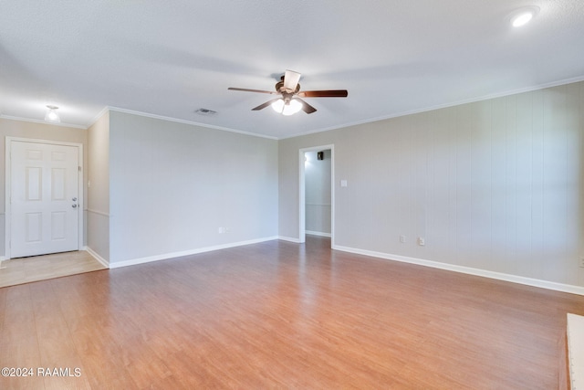 empty room with wood walls, ornamental molding, ceiling fan, and hardwood / wood-style flooring