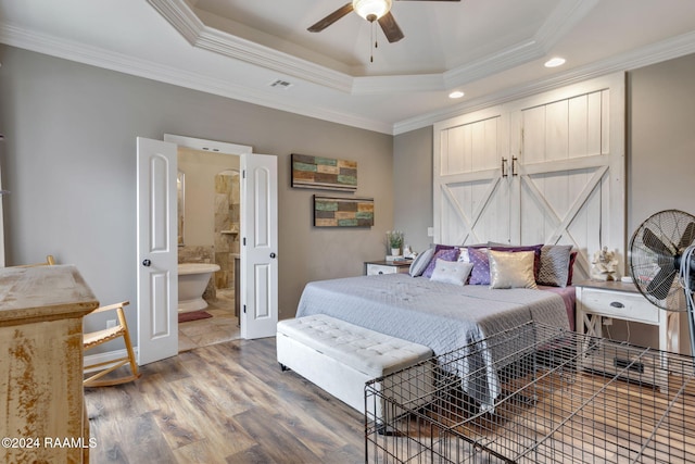 bedroom featuring ensuite bath, dark hardwood / wood-style floors, ceiling fan, a tray ceiling, and crown molding