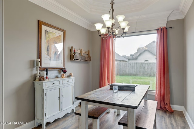 dining room featuring a tray ceiling, a notable chandelier, crown molding, and light hardwood / wood-style flooring