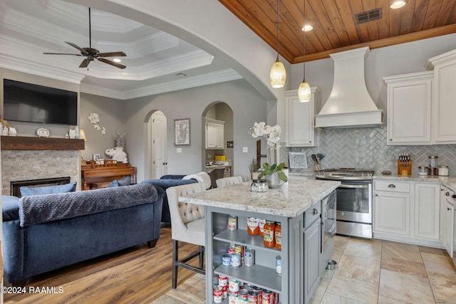 kitchen featuring white cabinetry, stainless steel range with electric cooktop, a kitchen island, crown molding, and premium range hood