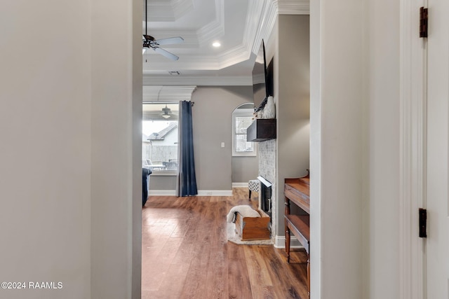 hall featuring a tray ceiling, wood-type flooring, and crown molding