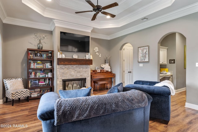 living room with a tray ceiling, hardwood / wood-style flooring, and crown molding