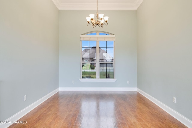 empty room featuring wood-type flooring, crown molding, and an inviting chandelier