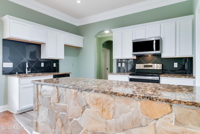 kitchen featuring white cabinetry, decorative backsplash, light stone countertops, and appliances with stainless steel finishes