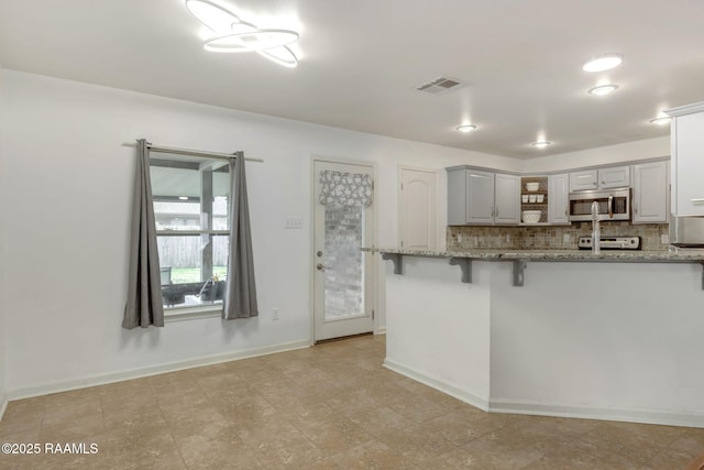 kitchen featuring light stone countertops, a breakfast bar, range, and decorative backsplash