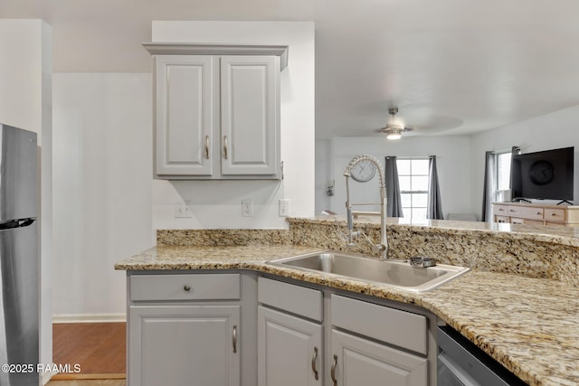 kitchen featuring sink, white cabinets, ceiling fan, stainless steel appliances, and light stone countertops