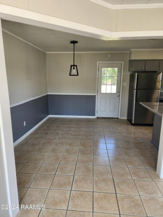 unfurnished dining area with wooden walls, crown molding, and tile patterned flooring