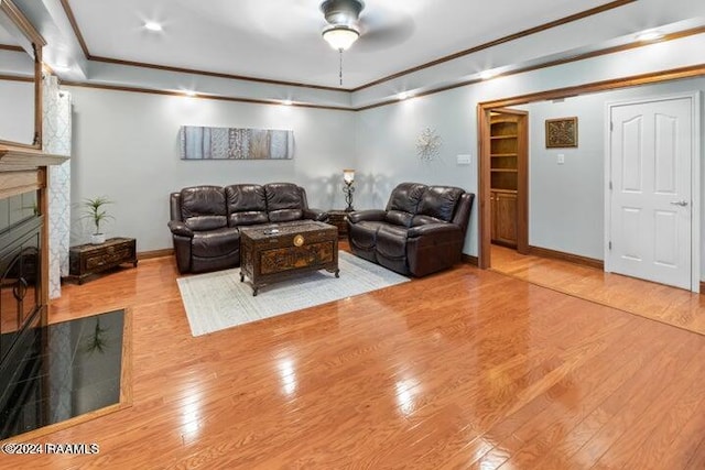 living room with ceiling fan, light hardwood / wood-style flooring, ornamental molding, and a tile fireplace