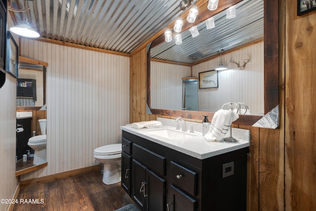 bathroom featuring wood-type flooring, ornamental molding, vanity, wooden walls, and toilet