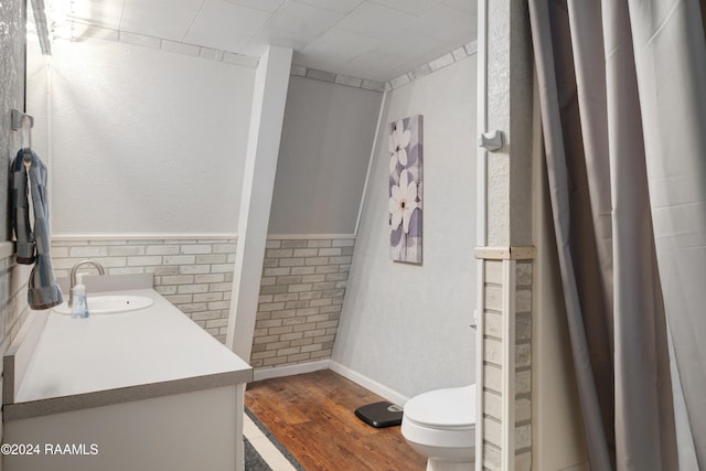 bathroom featuring tile walls, hardwood / wood-style floors, vanity, and toilet