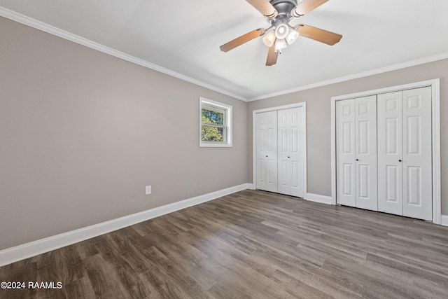 unfurnished bedroom featuring crown molding, hardwood / wood-style floors, multiple closets, and ceiling fan