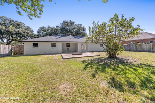 rear view of property featuring an outdoor fire pit, a patio, and a lawn