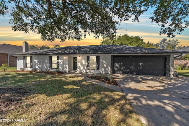 ranch-style home featuring a garage and a yard